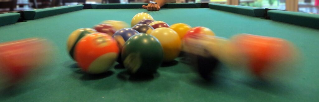 A player striking a ball in a pool table.