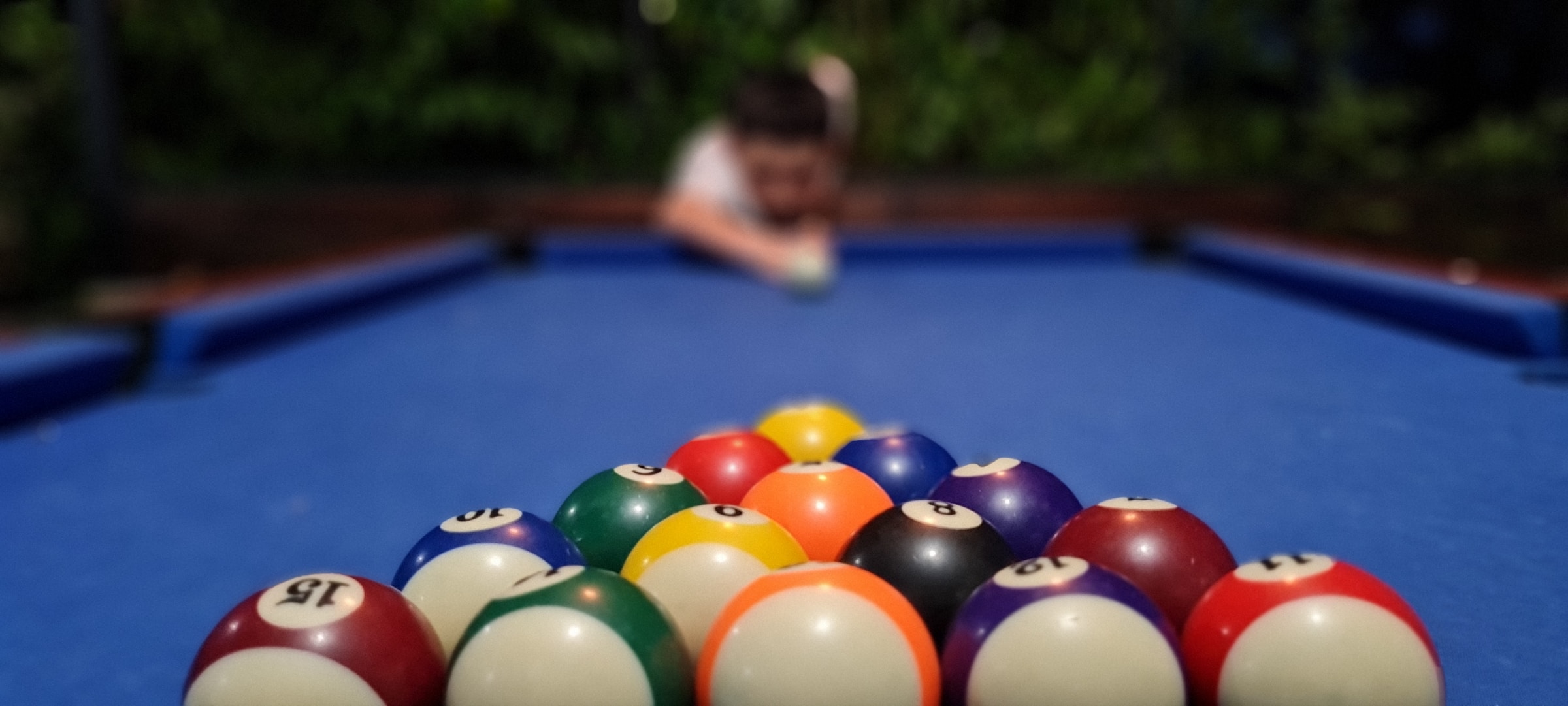 A billiards player is preparing to strike the cue ball on a small pool table.